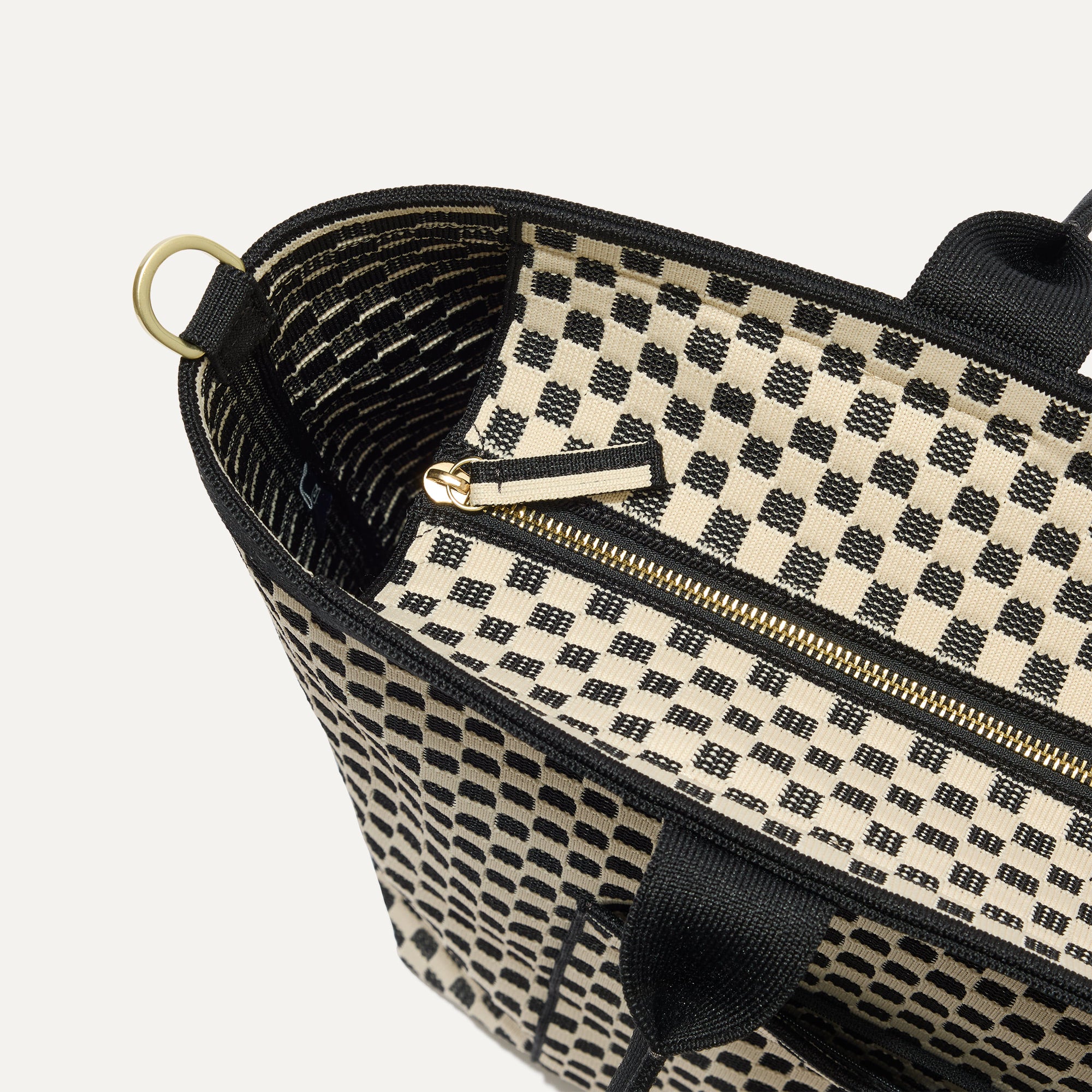A close up of The Zip Travel Tote in Tuxedo Midi Check focusing on the zip closure and handles.